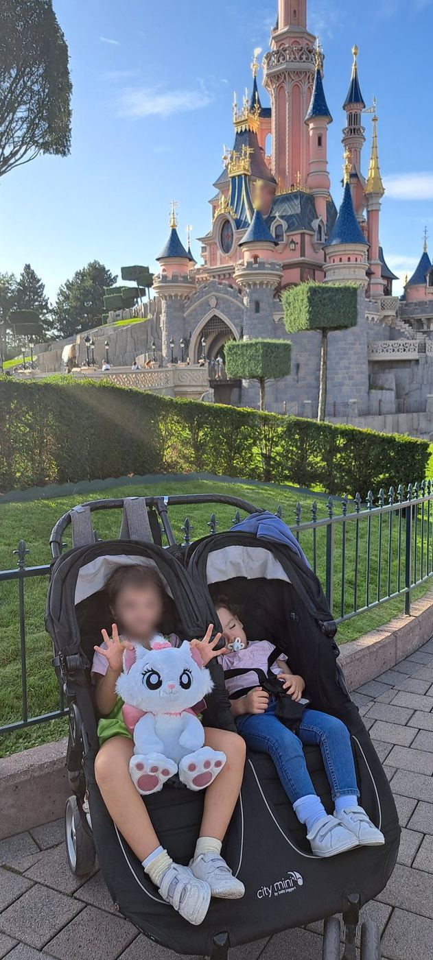 El carrito doble con las dos pequeñas dentro, delante del castillo de Disneyland Paris®, en octubre de 2023